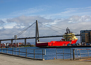 Ein großes Frachtschiff vor einer hohen Brücke.