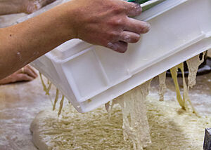 Baguette-Teig wird aus einer Teigwanne auf die bemehlte Arbeitsfläche gekippt.