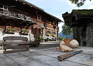 Auf einem rustikalen Holztisch liegt ein kräftig ausgebackenes Brot mit Mehl auf der Kruste.