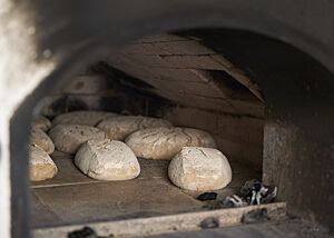Bemehlte Brotteiglinge liegen in einem Holzbackofen.