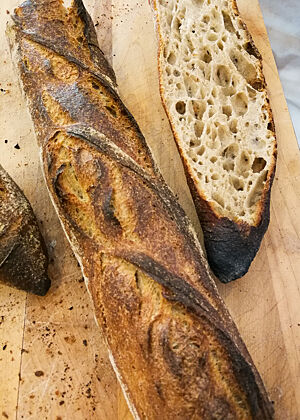 Ein dunkel ausgebackenes Baguette zeigt im Anschnitt seine grobporige Krume.