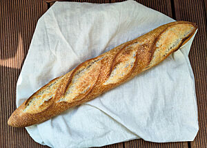 Goldbraun gebackenes Baguette mit vier Einschnitten und Süßbläschen auf der Kruste.