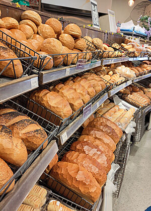 Viele goldbraune Weißbrote und Brötchen auf mehreren Ebenen in einem Regal.