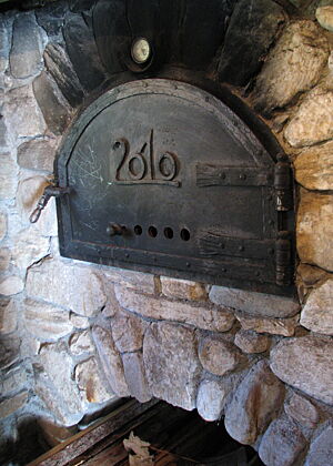 Die geschlossene Tür des Holzbackofens trägt die Aufschrift „2010“.