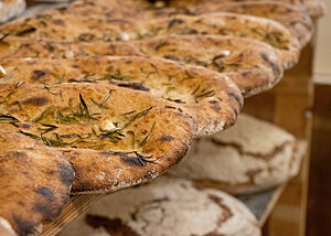 Die Focaccia sind mit Rosmarinnadeln und Knoblauchzehen bestreut und glänzen von Olivenöl.