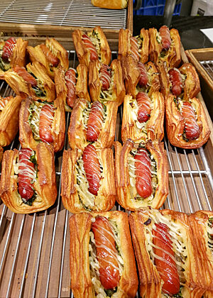 In Plunderteig gebackene Würstchen liegen auf einem Gitterrost.
