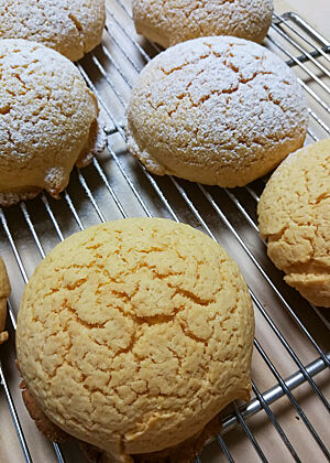 Die goldgelb ausgebackenen Melonenbrötchen erinnern mit der von vielen kleineren Rissen durchzogenen Oberfläche etwas an Galiamelonen.