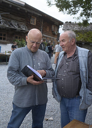 Werner Nagele (rechts) spricht mit Arnd Erbel (rechts), der in einem Buch blättert.