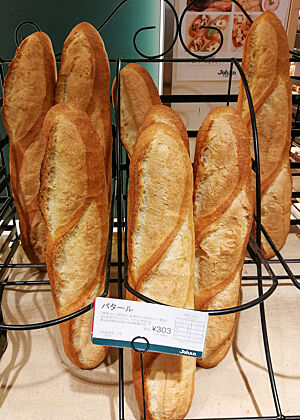 Mehrere Baguettes stehen in einem Ständer in der Auslage einer Bäckerei in Japan.