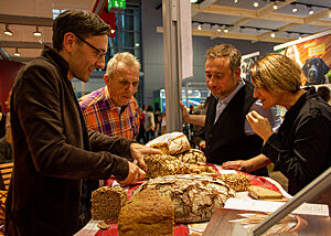 Stevan Paul und Daniela Haug besuchen den Messestand von Lutz Geißler und begutachten das von ihm angebotene Brot.