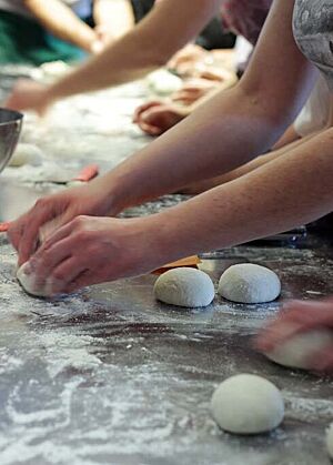 Ein Teilnehmer des Crashkurses Teigbearbeitung formt Brötchenteiglinge.