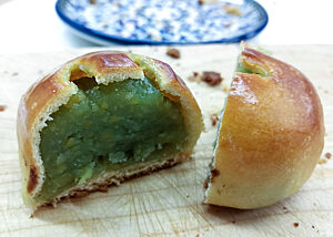 Das Anpan mit glänzender Kruste zeigt angeschnitten die glänzende grüne Füllung.