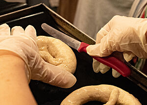 Die dicken Bäuche der gelaugten, schwäbisch geformten Brezeln werden tief mit einem Wellenschliffmesser eingeschnitten.