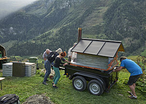 Der auf einem Anhänger gelagerte mobile Holzbackofen wird auf eine Wiese geschoben.
