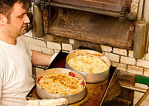 Ein Bäcker holt zwei Kuchen aus dem Ofen.