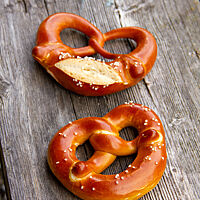 Zwei mit Salz bestreute Laugenbrezel mit und ohne eingeschnittenem Brezelbauch. 