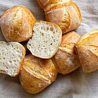 Goldgelbe, quadratische Brötchen mit tiefem, diagonalem Einschnitt wurden jeweils paarweise angeschoben gebacken.