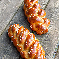 Zwei Hefezöpfe, aus vier und fünf Strängen geflochten, sind goldbraun ausgebacken und mit Hagelzucker bestreut.
