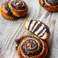 Eine Mohnschnecke im Anschnitt zeigt im hell-dunkel-Kontrast die Schichten aus Mohn und Teig.