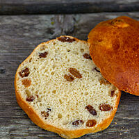 Das aufgeschnittene Rosinenbrötchen bringt die Sultaninen in der lockeren, kleinporigen Krume zum Vorschein.