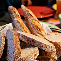 Mehrere Scheiben Mischbrot und zwei Stangen Baguette liegen in einem Brotkorb.