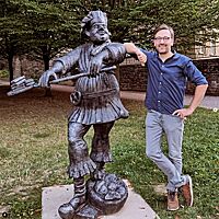 Lutz steht neben der Eierscheckenbäcker-Skulptur in Freiberg/Sachsen.