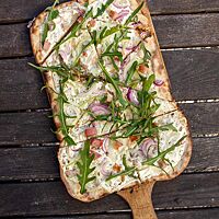 Nach dem Backen wurde der Flammkuchen zusätzlich zu Zwiebeln und Speck mit frischem Rucola belegt.