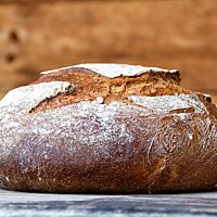Das Bananenbrot, kräftig ausgebacken, liegt auf einer rustikalen Holzplatte.