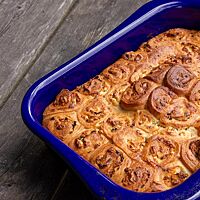 In einer blauen, rechteckigen Auflaufform liegt die goldgelb ausgebackene Pitka, bestehend aus vielen mit Feta gefüllten und eingewickelten Röllchen.