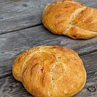 Zwei flache goldgelbe Fladen mit flachem Ausbund liegen auf einem rustikalen Holztisch.