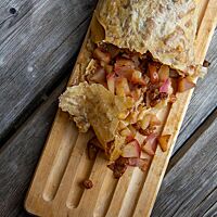 Der aufgeschnittene Dinkelstrudel ist mit Apfelstückchen und Rosinen gefüllt.