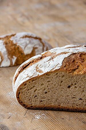 Der Anschnitt des Bauernbrotes zeigt die lockere, kleinporige Krume umgeben von einer mittelbraunen, knusprigen Kruste.