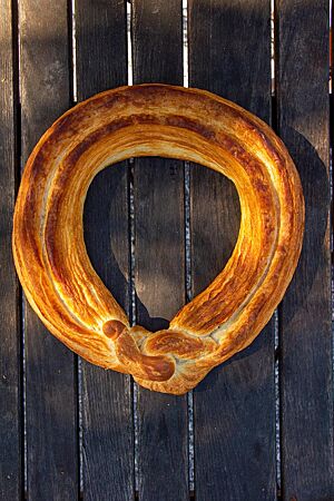 Die ringförmige Neujahrsbrezel, goldbraun ausgebacken, liegt auf einem dunklen Holztisch.
