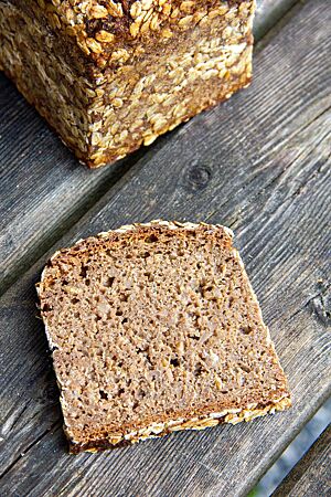 Das Schwarzbrot im Anschnitt zeigt die ganzen Roggenkörner in der saftigen Krume.