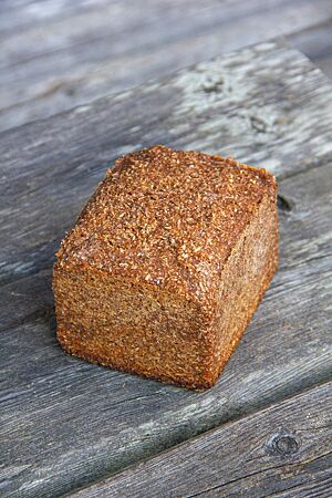 Das kräftig ausgebackene Roggenschrotbrot in Form eines Kastenbrotes liegt auf einem rustikalen Holztisch.