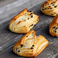 Die kleinen, rechteckigen Klöben mit goldgelb ausgebackener Kruste liegen auf einem rustikalen Holztisch.