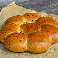 Acht kleine Weizenbrötchen liegen aneinandergebacken in Form einer Blüte auf Backpapier.