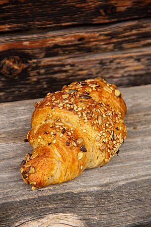 Auf der Oberfläche des hellbraun ausgebackenen Croissants sind Sonnenblumenkerne, Sesam, Leinsamen und Kürbiskerne zu sehen.