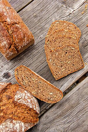 Sowohl freigeschoben als auch in Kastenform zeigt das angeschnittene Saatenbrot seine dunkelbraune, saftige Krume.