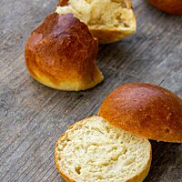 Auseinandergezupft und aufgeschnitten zeigen zwei Brioche-Buns die wattige, lockere Krume.
