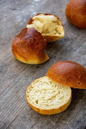 Auseinandergezupft und aufgeschnitten zeigen zwei Brioche-Buns die wattige, lockere Krume.