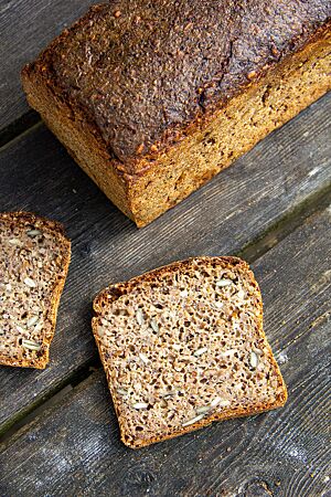 Das aufgeschnittene Brot zeigt eine saftige Krume mit sichtbaren Saaten.