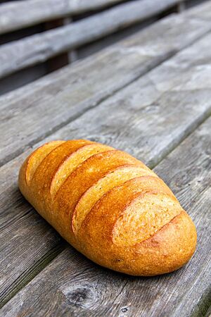 Das Dinkel-Weißbrot wurde als länglicher Laib geformt mit parallelen Querschnitten in der goldgelben Kruste.