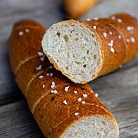 Die ungefüllten, mit Salz und Kümmel bestreuten Almstangerl zeigen im Anschnitt ihre weiße Krume.