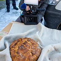Eine Kamerafrau richtet die Kamera auf das Neudorfer Seelenbrot, das auf einem Leinentuch liegt.