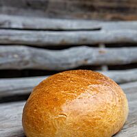 Ein ovales Weißbrot mit glänzender, glatter Kruste liegt auf einem rustikalen Holztisch.