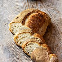 Das aufgeschnittene Landbrot zeigt die helle, grobporige Krume unter der kräftig ausgebackenen, matten Kruste.