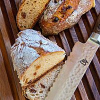Das Weihnachtsbrot liegt angeschnitten auf dem Schneidebrett aus Nussbaumholz.