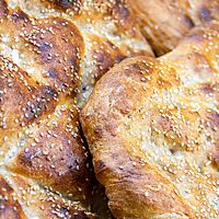 Die kräftig ausgebackenen Fladenbrote sind auf der leicht glänzenden Kruste mit hellem Sesam bestreut.