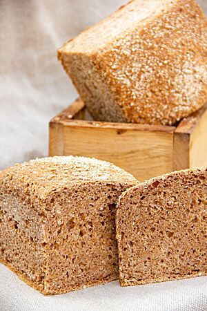 Ein Weizenschrotbrot im Anschnitt zeigt das Schrot in der saftigen Krume.
